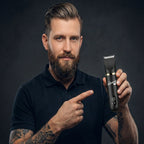 Man holding a black hair trimmer and pointing at it against a dark background